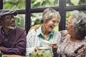 Three older adults smiling and drinking coffee