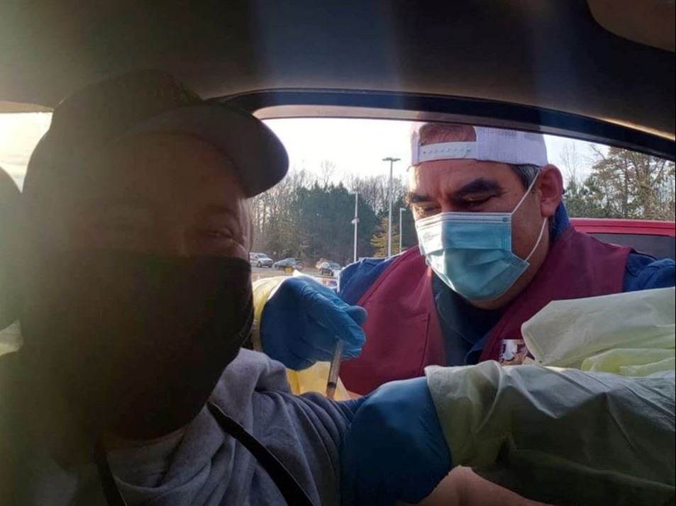 John Herrera administering a shot to New Hope Fire Chief Charles Bowden