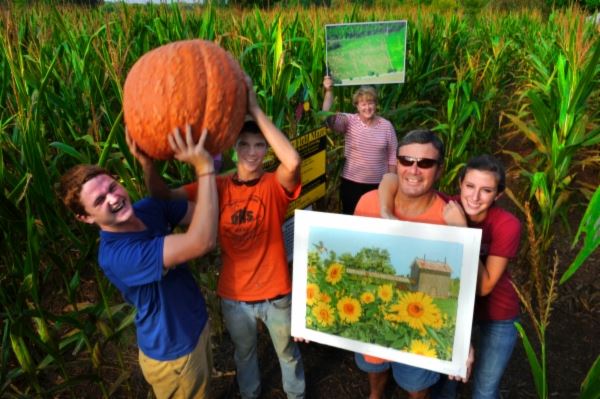 Family holding large pumpkin at Corn Maze