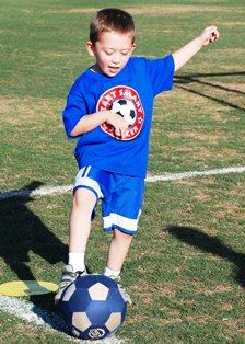 Young boy kicking soccer ball