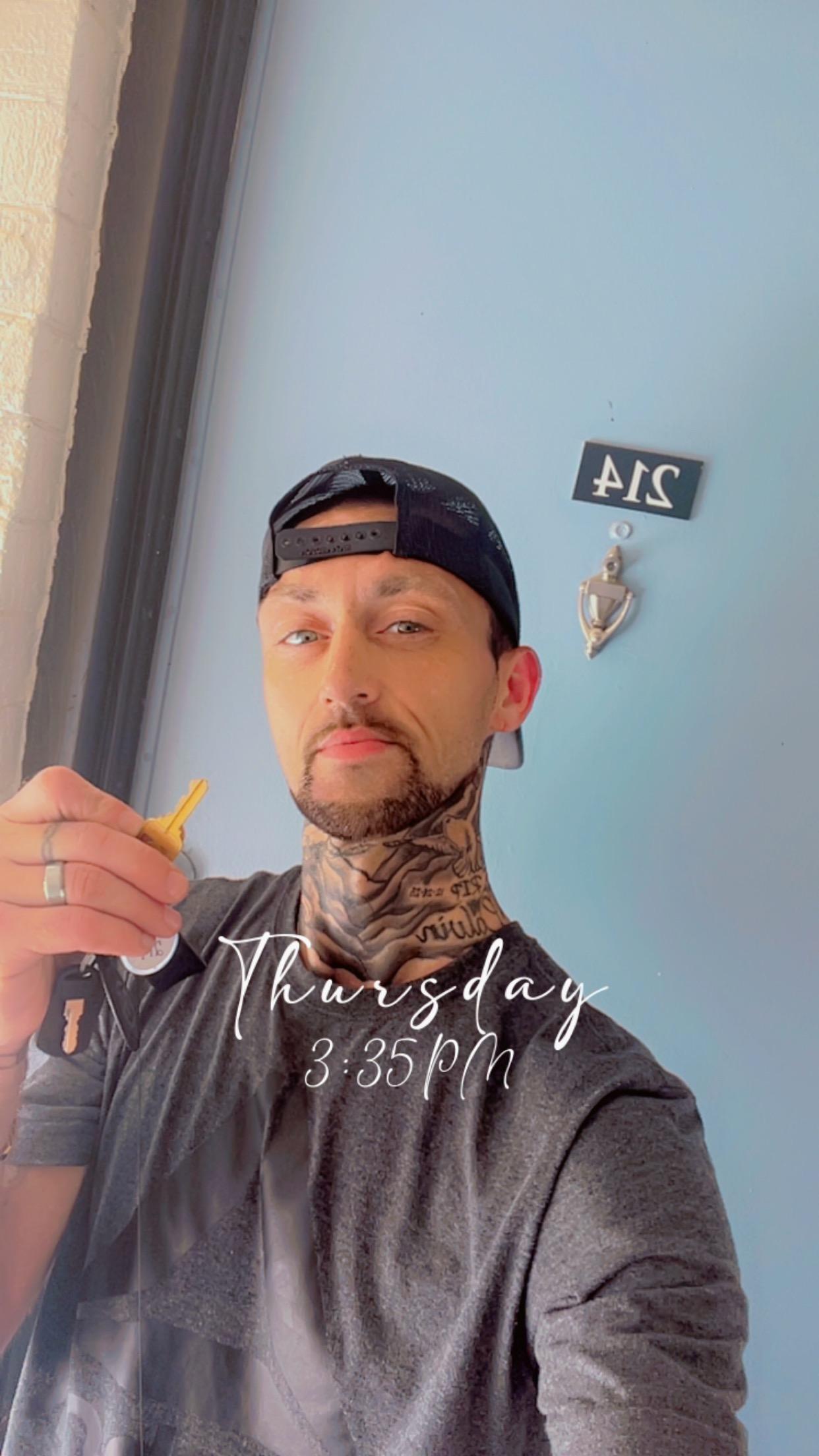 LRC participant Dustin standing in front of his new apartment door holding a key